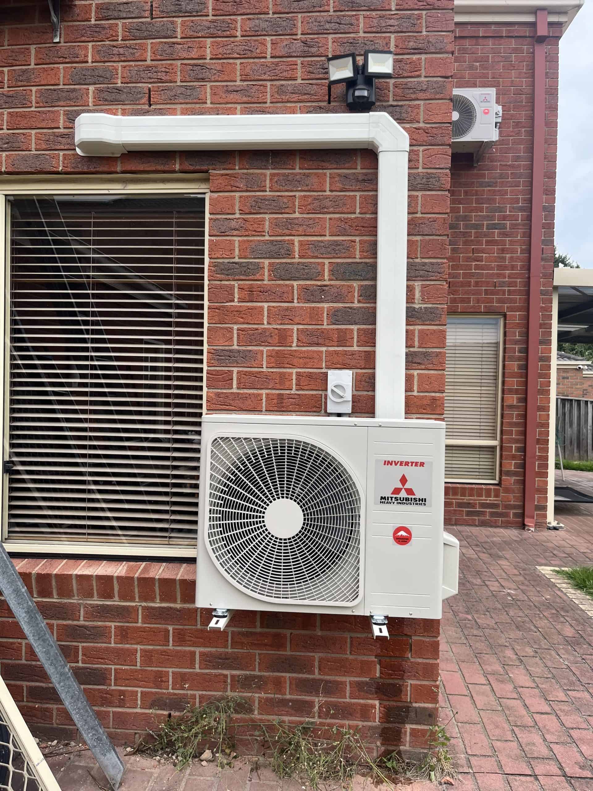 Air conditioning unit installed on exterior brick wall of a building outside.