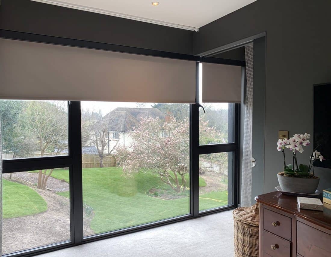 Modern window with roller blinds inside a residential living room overlooking the garden.