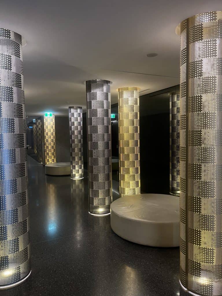 Luminescent decorative columns inside a modern building, mounted on polished indoor flooring.