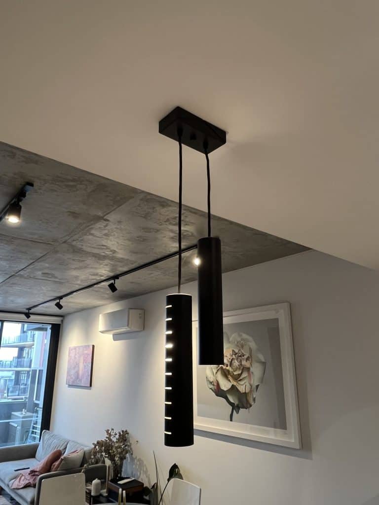 Modern black pendant lights hanging inside on a white ceiling.